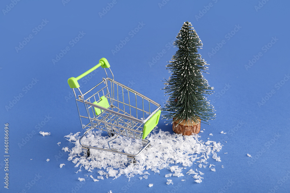 Shopping cart with Christmas tree and snow on blue background