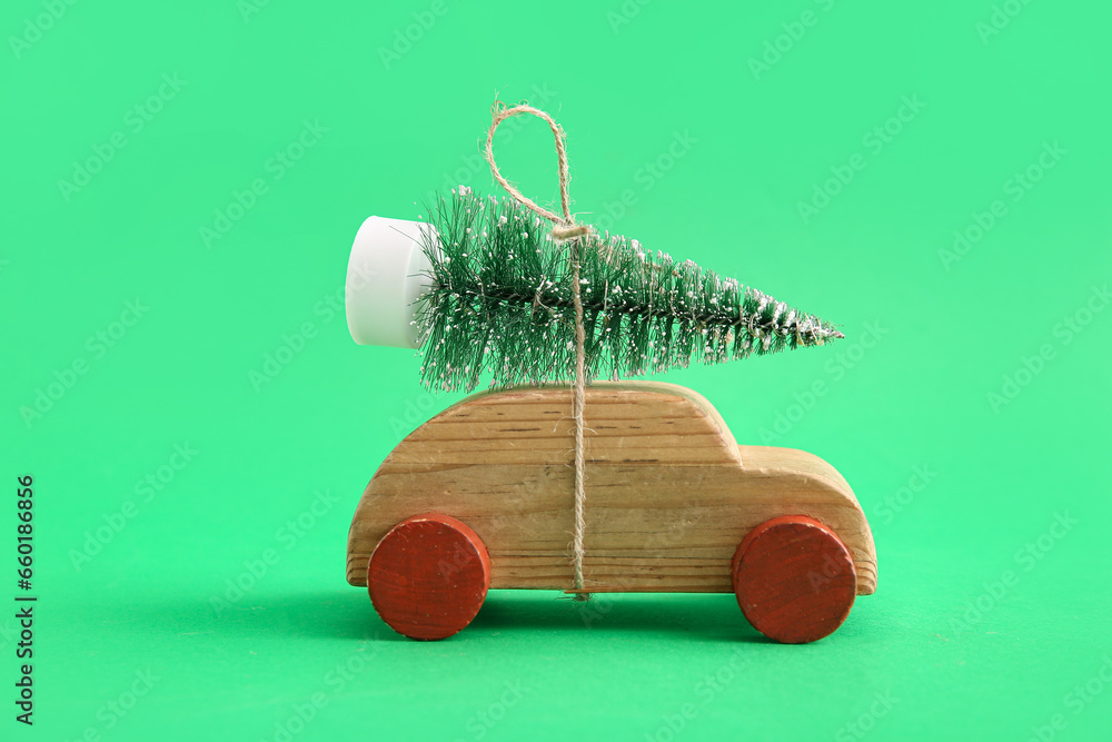 Christmas tree and wooden toy car on green background