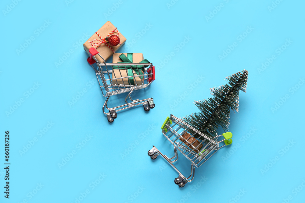 Shopping carts with Christmas tree and gift boxes on blue background