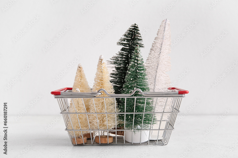 Shopping basket with Christmas trees on white background