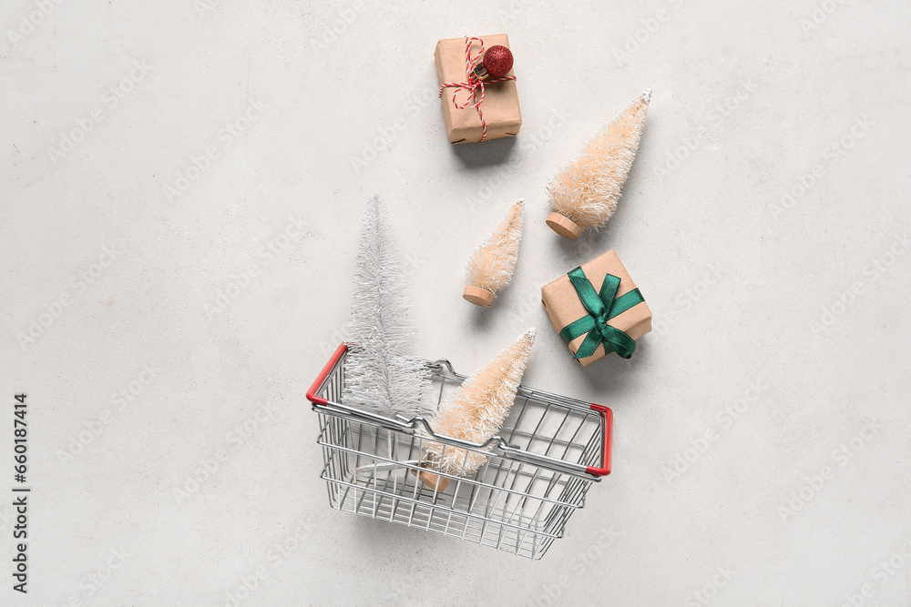 Shopping basket with white Christmas trees and gift boxes on beige background