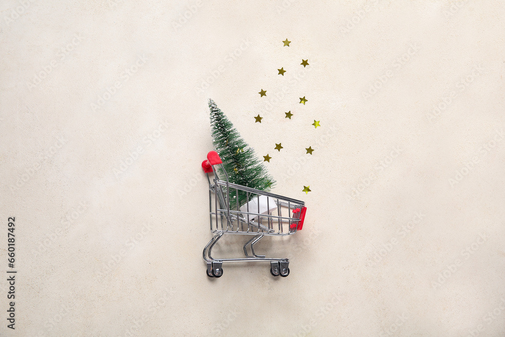 Shopping cart with Christmas tree on beige background