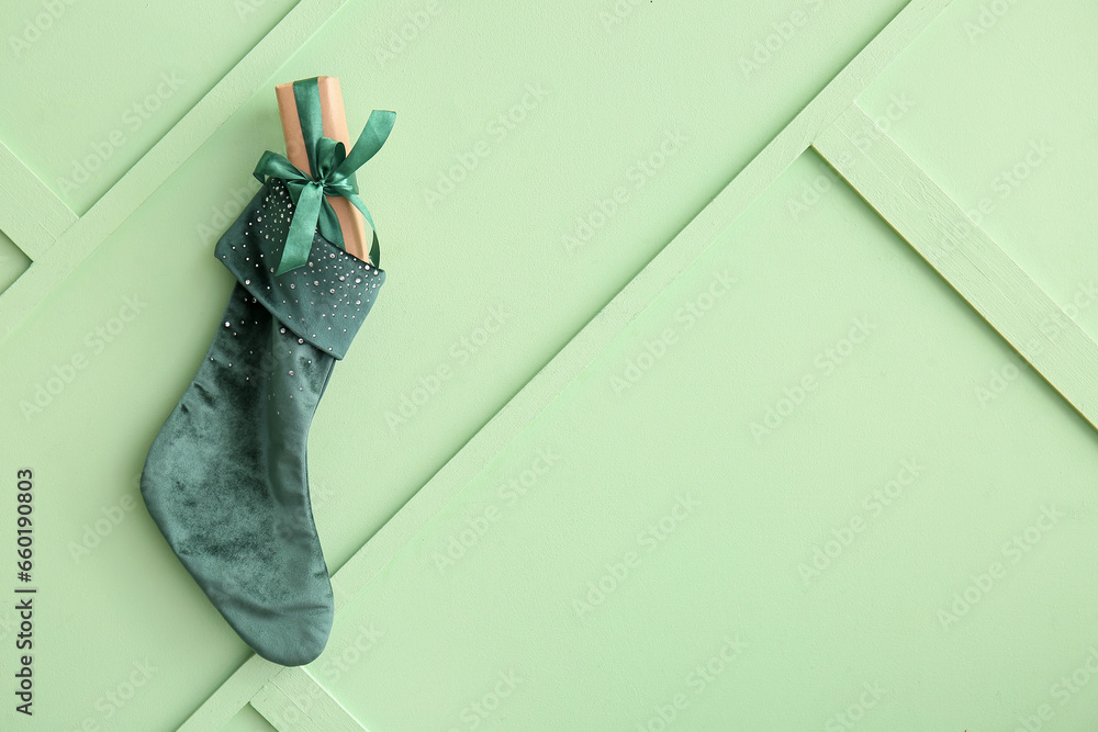 Beautiful Christmas sock with gift box hanging on green wall