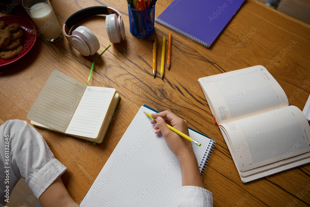 High angle view closeup on little student hands writing in copybook