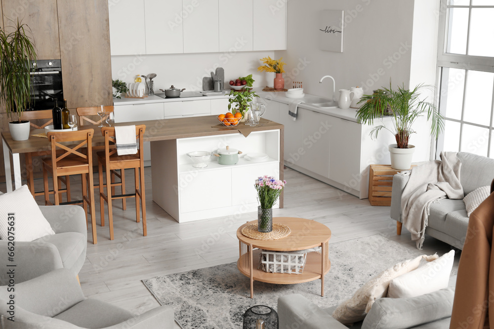 Interior of light open plan kitchen with coffee table and grey sofa