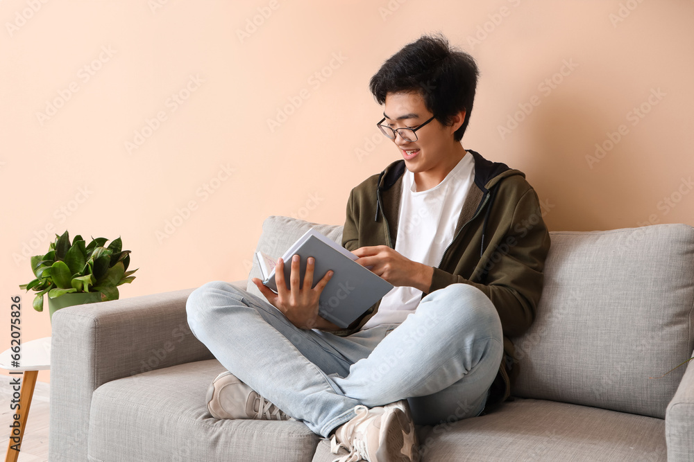 Young Asian man reading book on his day off at home