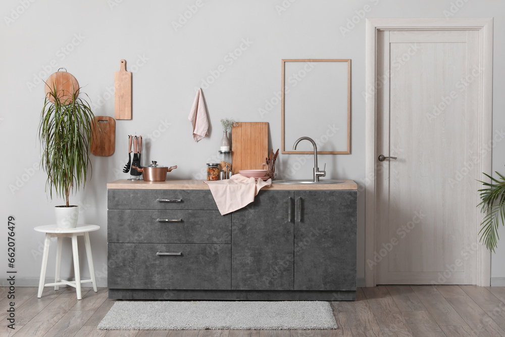 Grey counters with cutting boards, sink, utensils and cooking pot in kitchen