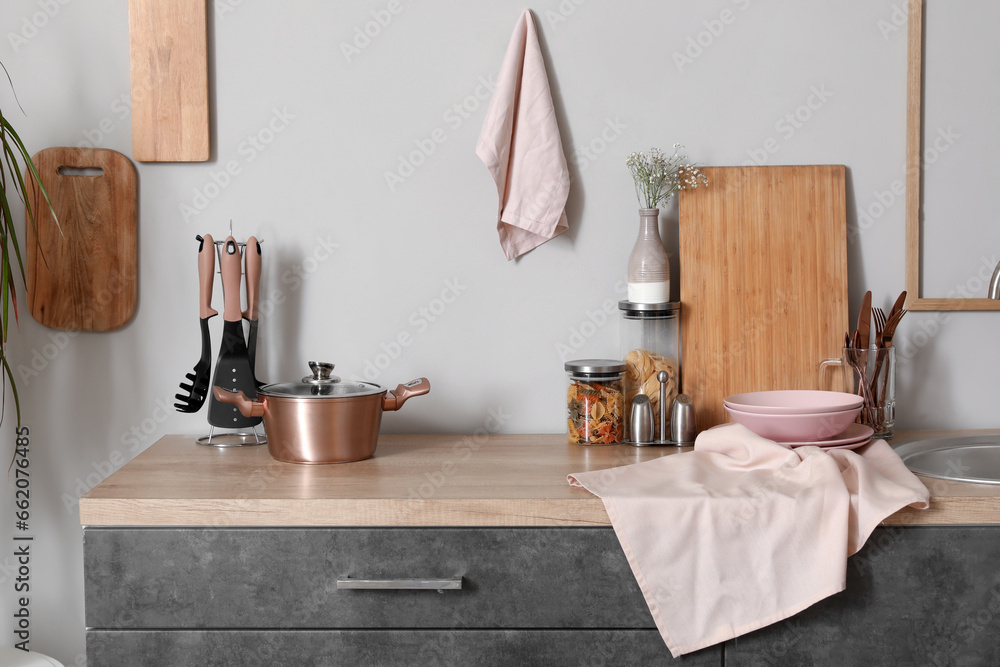 Grey counters with cutting boards, utensils and cooking pot in kitchen