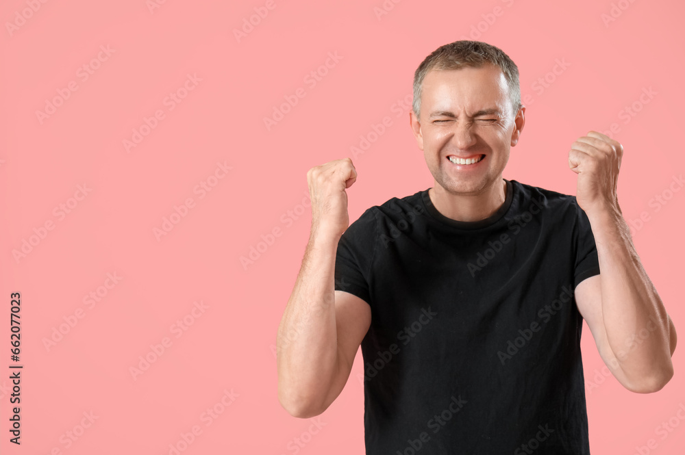 Portrait of happy mature man celebrating success on pink background