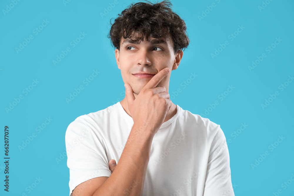 Portrait of pondering young man on blue background