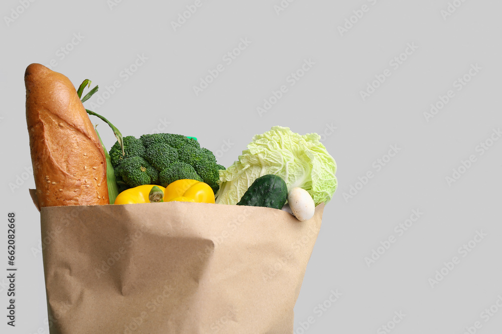 Paper shopping bag with fresh vegetables on grey background