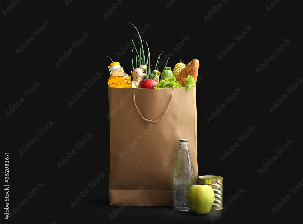 Paper shopping bag with different fresh products on black background