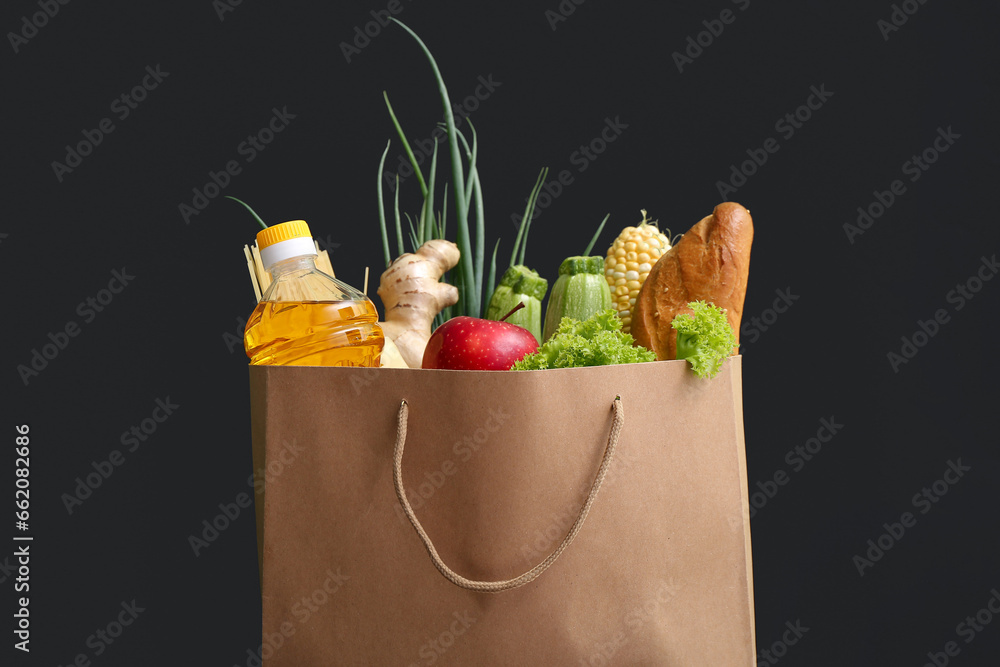 Paper shopping bag with different fresh products on black background