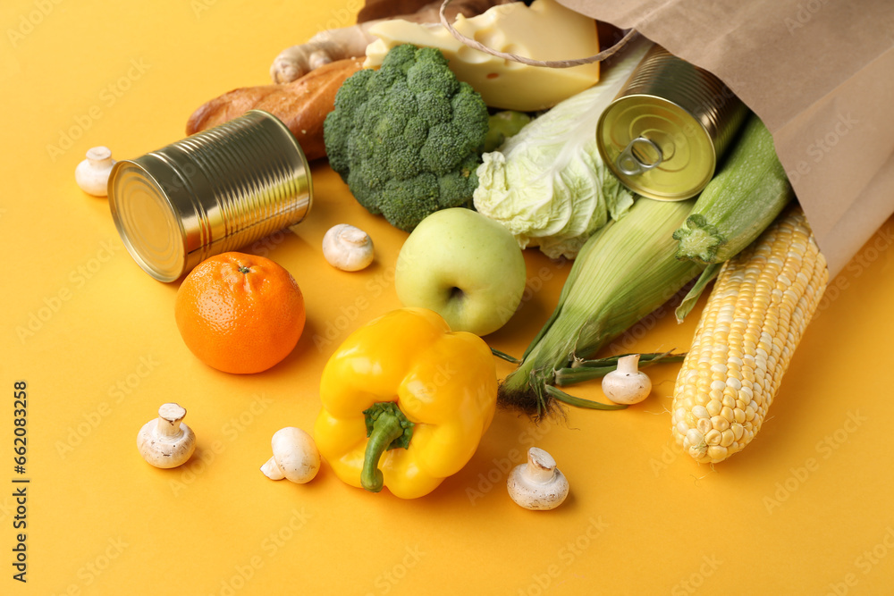 Paper shopping bag with different fresh products on yellow background