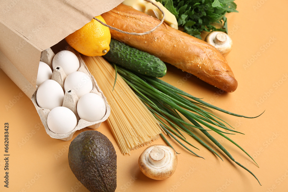 Paper shopping bag with different fresh products on orange background