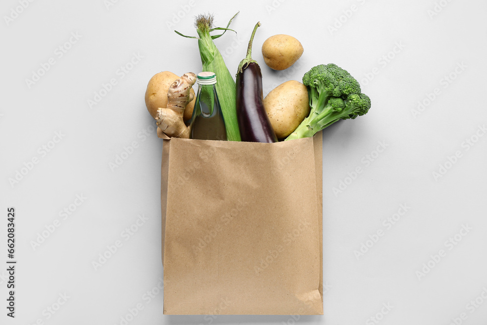 Paper shopping bag with fresh vegetables on grey background