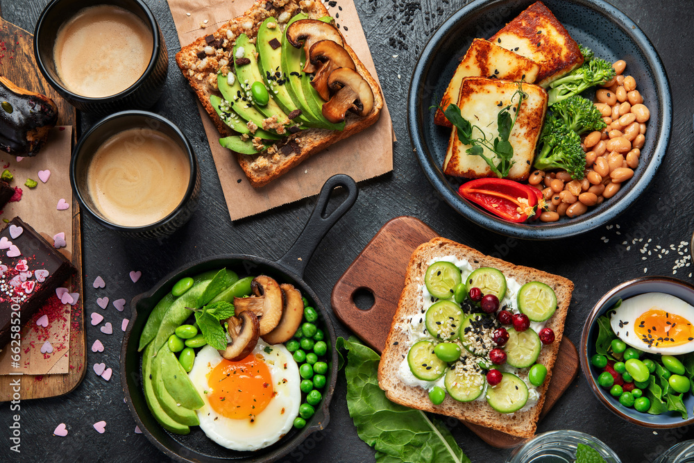 Tasty food with avocado toast, vegetables, eggs on dark background. Helthy breakfast concept