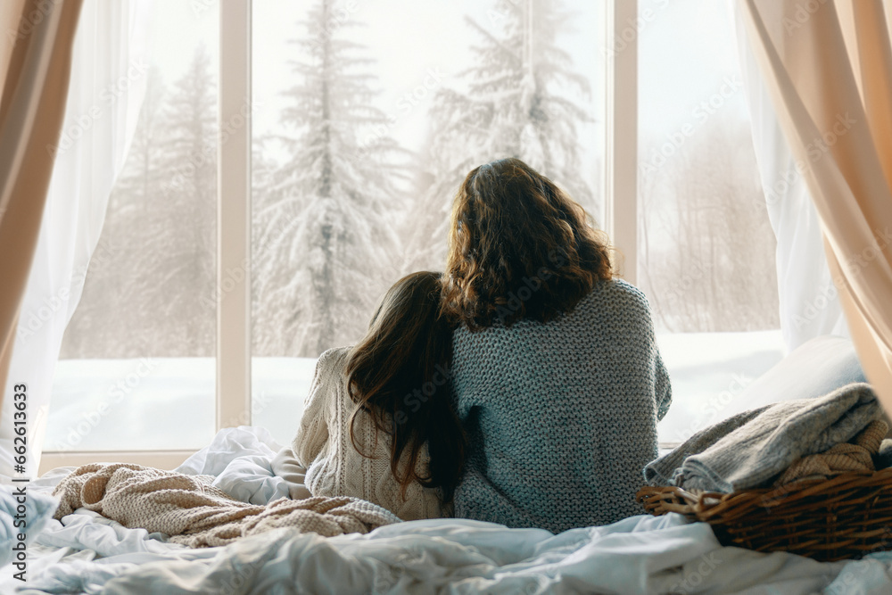 Mother and daughter enjoying winter nature in the  window