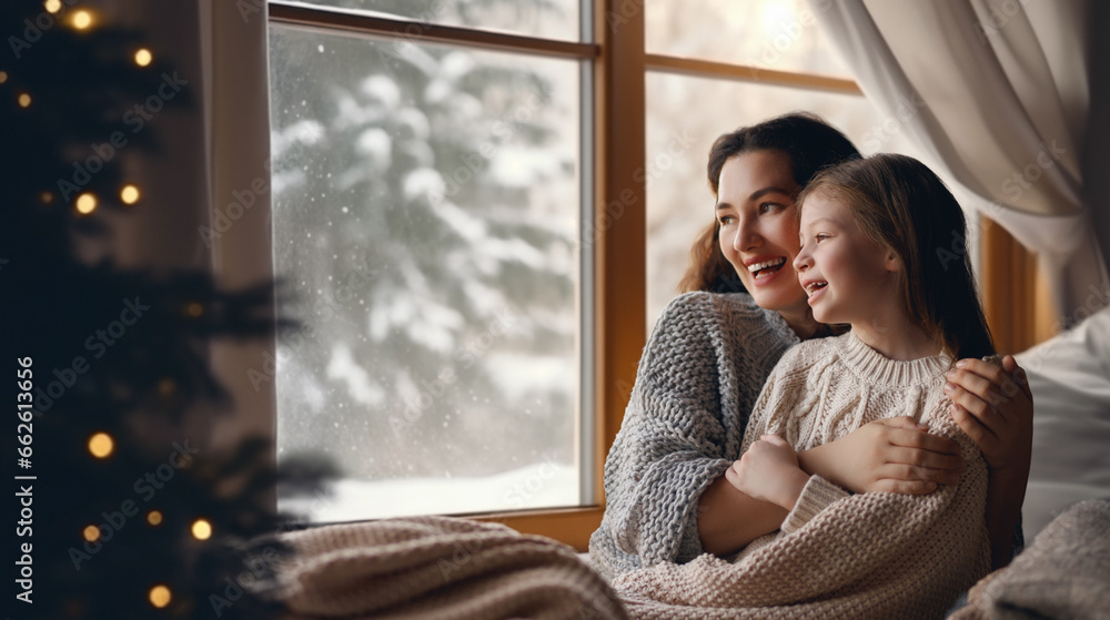 Mother and daughter enjoying winter nature in the  window