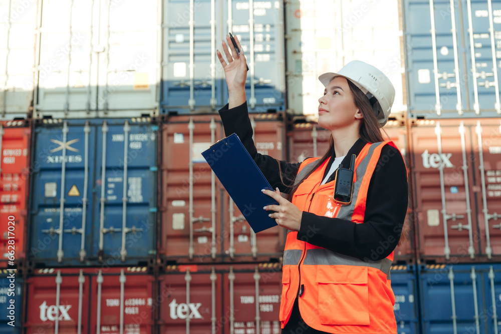 Female engineer with clip- folder wearing white helmet and vest in container terminal port