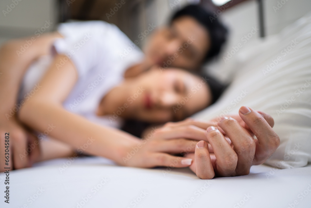 Asian attractive young couple lying down on bed to sleep in bedroom. 