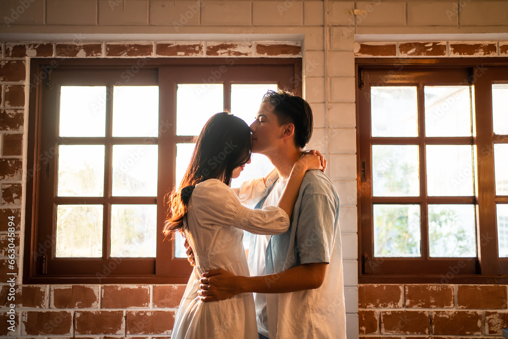 Asian young man and woman kissing each other in living room at home. 