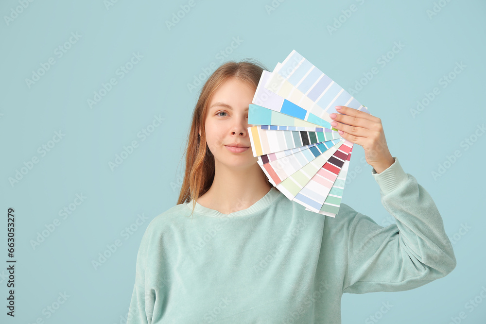 Young woman with many color samples on light blue background