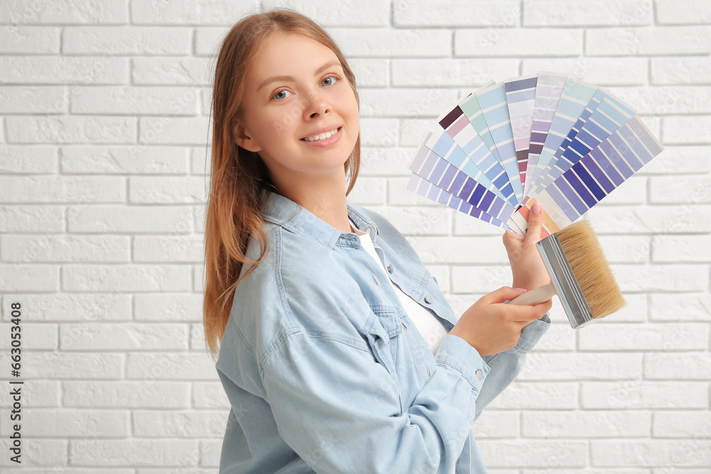 Young woman with color samples and brush on white brick background