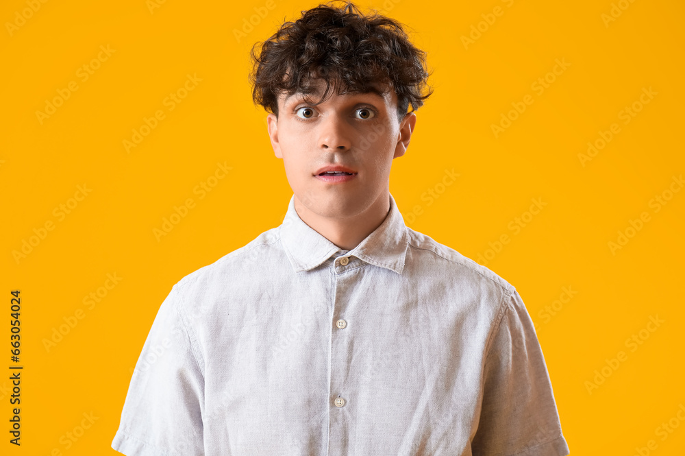 Portrait of shocked young man on orange background