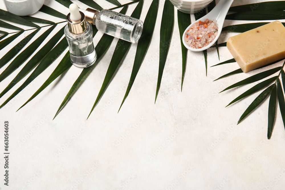 Composition with bath supplies and palm leaves on light background