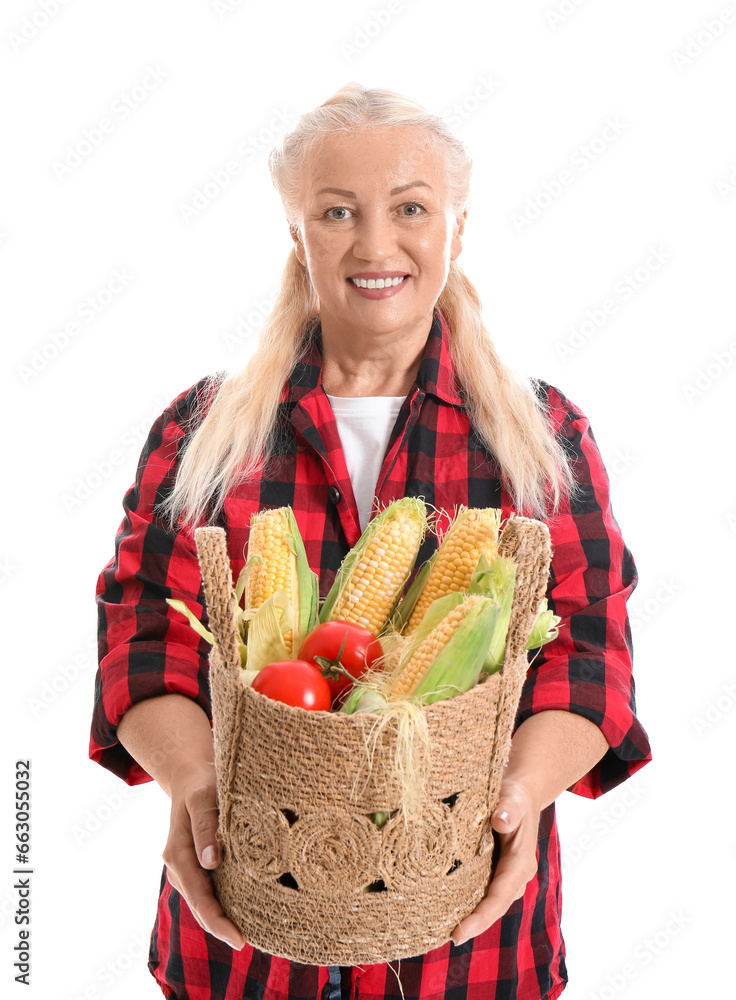 Mature female farmer with wicker basket full of different ripe vegetables isolated on white background