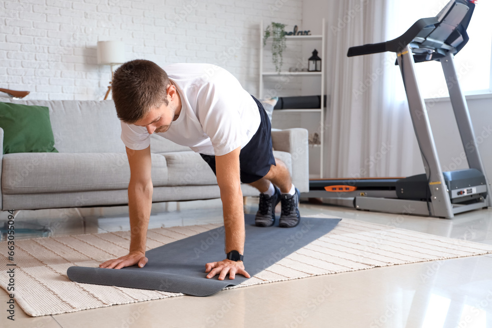 Sporty young man doing push-ups at home