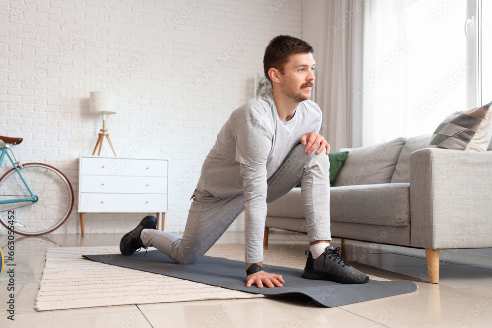 Sporty young man doing exercise at home