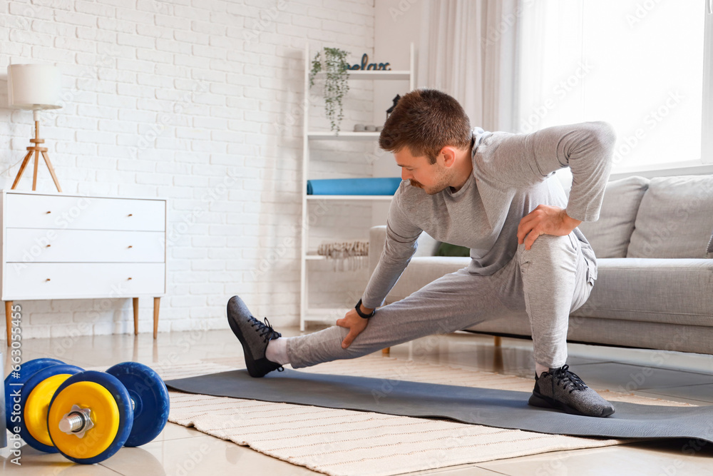 Sporty young man doing exercise at home