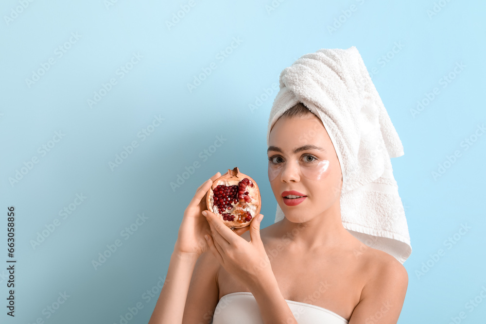 Young woman with under-eye patches and pomegranate on blue background