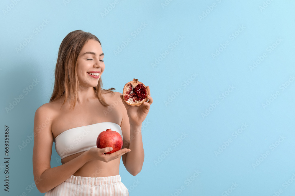 Young woman with pomegranate on blue background