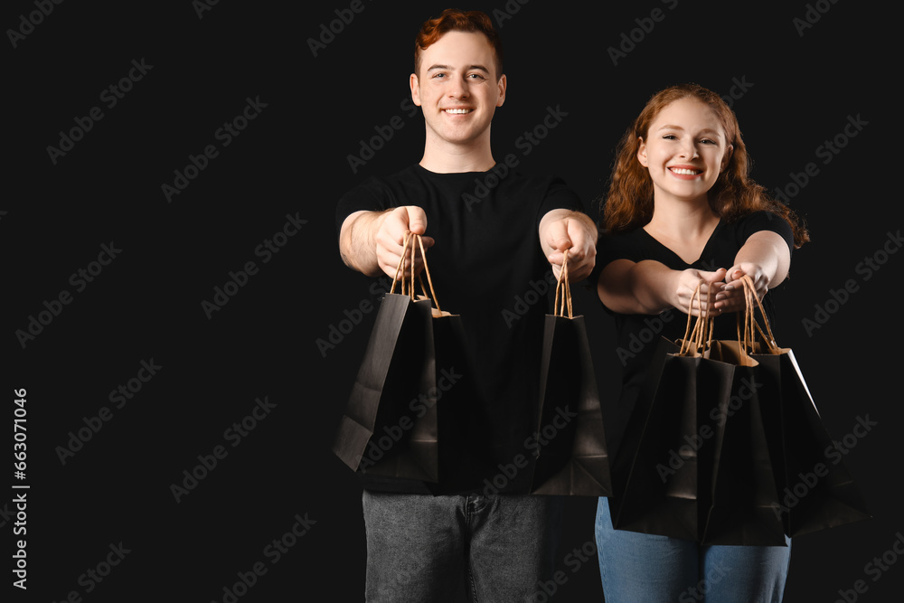 Young couple with shopping bags on dark background. Black Friday sale