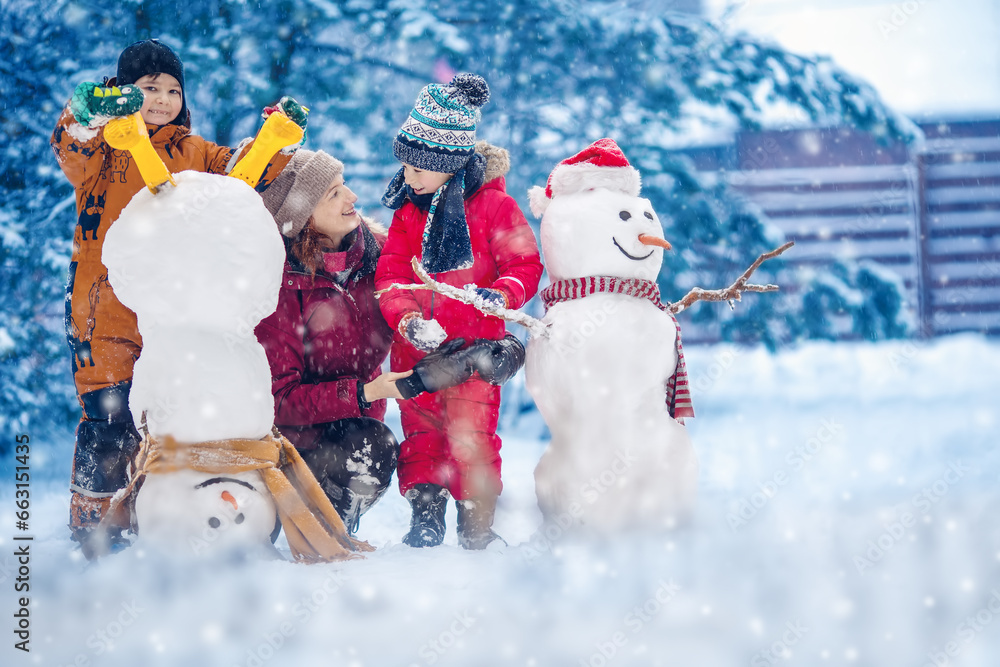 Family building a cute snowman in the snowy park.