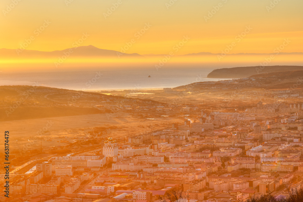 Morning aerial view of the city. Residential urban areas. Top view of buildings and streets at sunrise. In the distance the sea bay and mountains. City of Magadan, Magadan region, Far East of Russia.