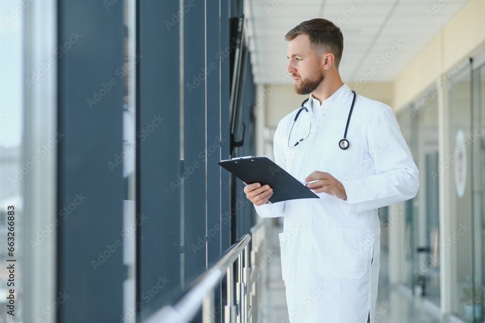 Portrait of handsome young doctor on hospital corridor