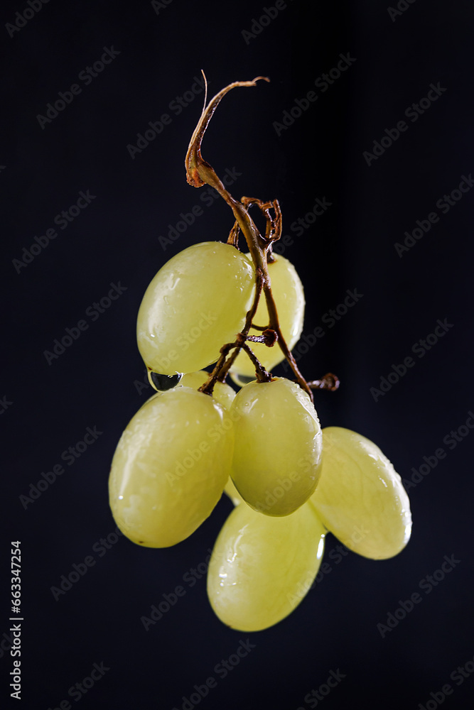 A small bunch of ripe green grapes on a black background.