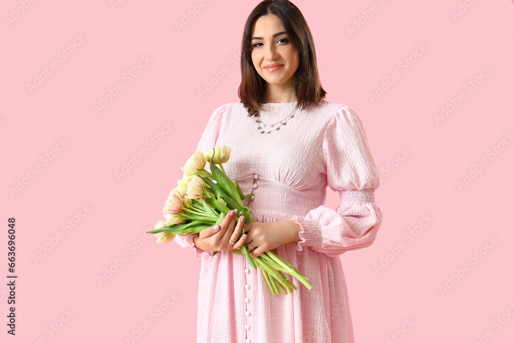 Young pregnant woman with tulips on pink background