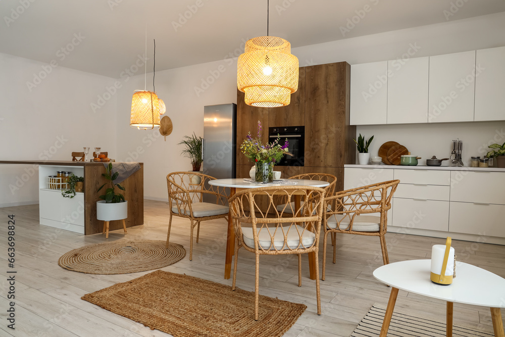 Interior of modern kitchen with dining table, island and glowing lamps