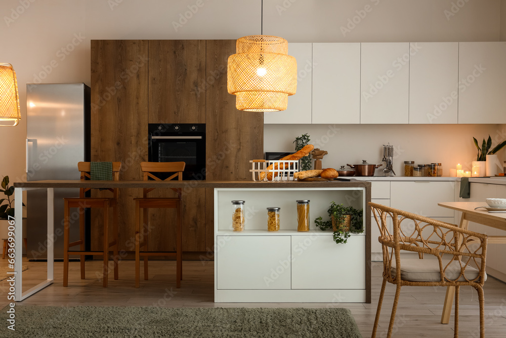 Interior of modern kitchen with island table and glowing lamps