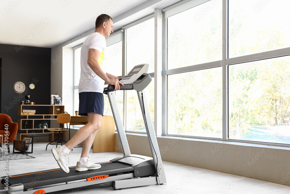 Sporty mature man training on treadmill at home