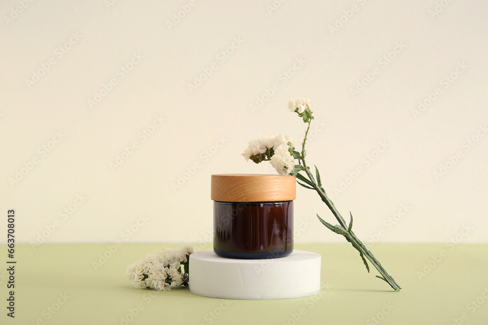 Composition with jar of cosmetic product, plaster podium and beautiful flowers on light background