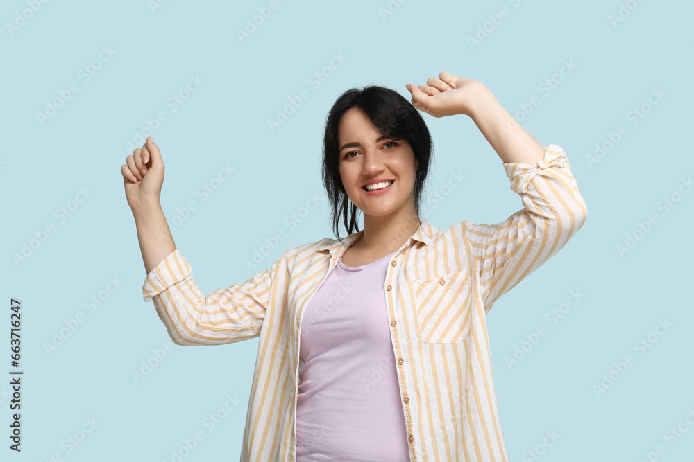 Portrait of happy young brunette on blue background