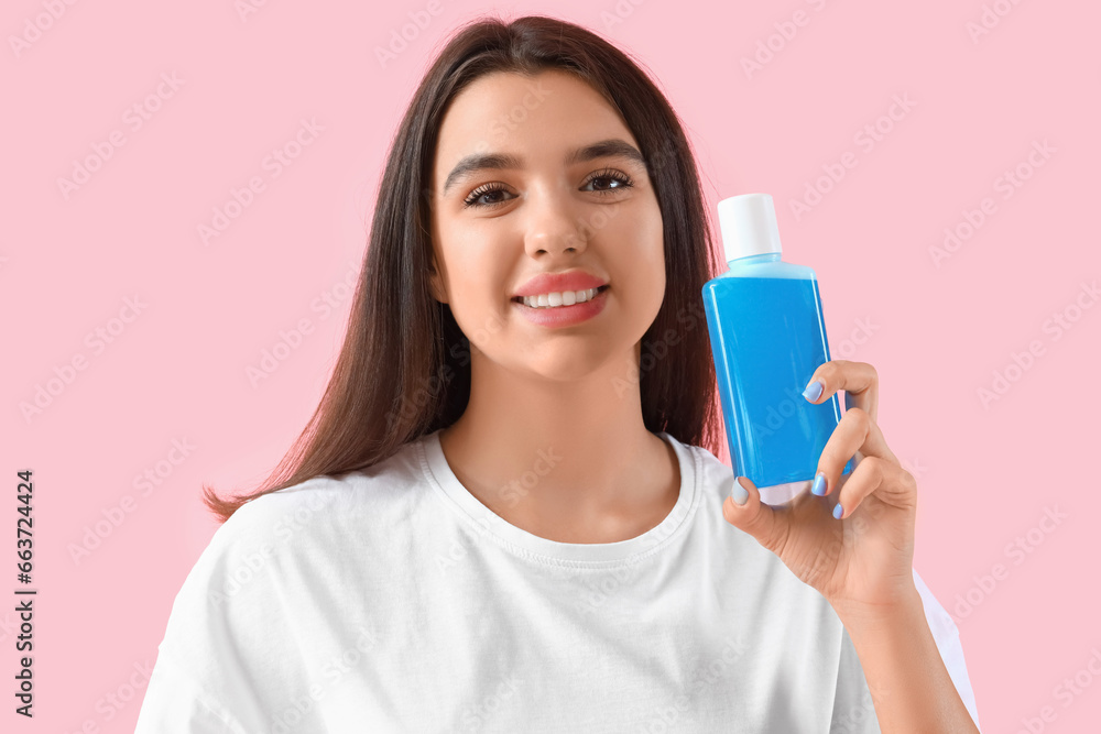 Smiling young woman with mouth rinse on pink background, closeup