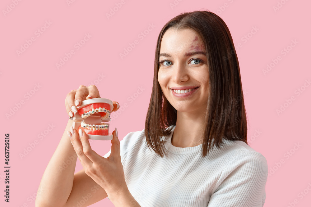 Smiling young woman with jaw model on pink background, closeup