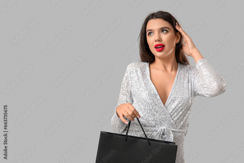 Beautiful woman with shopping bag on grey background. Black Friday sale